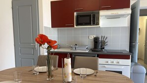 Une cuisine moderne équipée d’un four à micro-ondes, d’une machine à café et d’un coin repas avec des assiettes, des couverts et un vase de fleurs.
