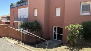 Un immeuble à plusieurs étages, doté d’un toit plat, d’une entrée abritée et d’un petit balcon situé à l’étage supérieur.