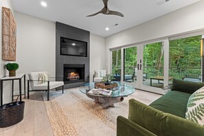 A modern living room with a fireplace, a glass coffee table, a sofa, and a view of the outdoors. - 2-bedroom Townhome In Peaceful Highlands Available For Monthly Rentals (Highlands)