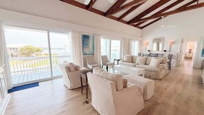 A spacious living room with a balcony, a sofa set, and a dining area. - Quiet Family Home | Close to Beach, Restaurants, Boating | Daily Activity Deals (Orange Beach)