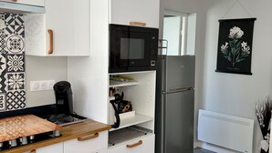 Eine moderne Küche mit weißen Schränken, einer schwarzen Mikrowelle, einem Edelstahlkühlschrank, einer Kaffeemaschine und einer strukturierten Spritzschutzwand.