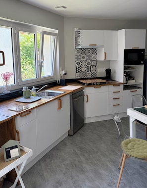 A modern kitchen with white cabinets, a wooden countertop, a built-in oven, and a microwave. - House with garden 500 metres from the beach (Meschers-sur-Gironde)