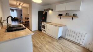 Una cocina moderna con horno integrado, refrigerador negro y encimera de madera.