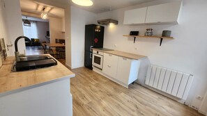 Une cuisine moderne dotée d’un four encastré, d’un réfrigérateur noir et d’un plan de travail en bois.