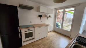 Eine Küche mit Kühlschrank, Backofen und einer Holzausziehtheke.