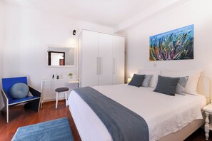 Ein Schlafzimmer mit Bett, Stuhl, Schreibtisch, Kleiderschrank und einem Bild an der Wand.