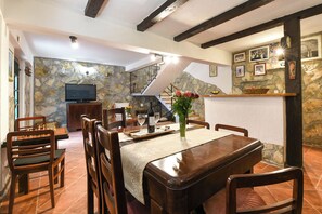 Ein Essbereich mit Steinwand, Holzmöbeln, einem Fernseher und einer Treppe.