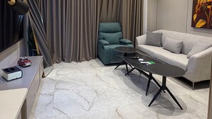 A modern living room with a sofa, a green armchair, a coffee table, a TV, and a painting on the wall. - 312 Tara-jre Jabal Al Lweibdeh With Stunning View (Amman)
