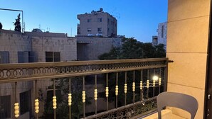 A balcony with two chairs, a table, and a view of buildings. - 312 Tara-jre Jabal Al Lweibdeh With Stunning View (Amman)