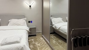 A hotel room with a large mirror, two beds, a nightstand, and a wall-mounted lamp. - 312 Tara-jre Jabal Al Lweibdeh With Stunning View (Amman)