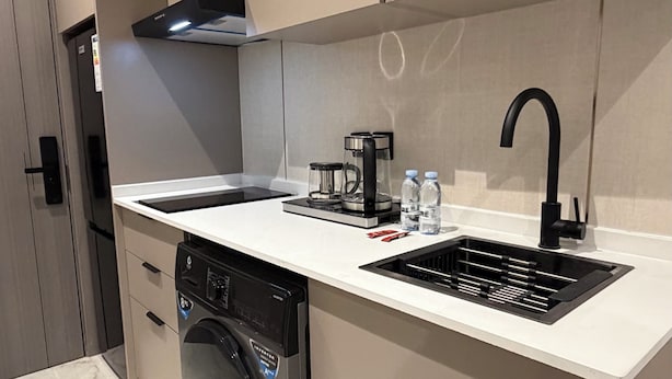 A modern kitchen with a built-in microwave, a coffee maker, and a washing machine. - 312 Tara-jre Jabal Al Lweibdeh With Stunning View (Amman)