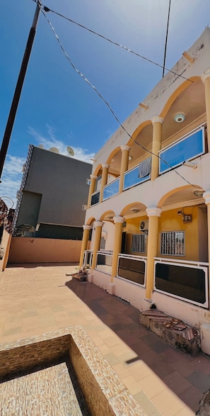 A two-story building with a courtyard, satellite dishes, and a tiled floor. - Aminah Signature Rentals - Bintou 3 Bedroom Brusubi (Brusubi)