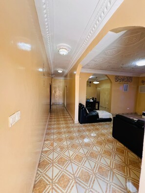 A hotel corridor with patterned flooring, a reception desk, and a bed. - Aminah Signature Rentals - Bintou 3 Bedroom Brusubi (Brusubi)