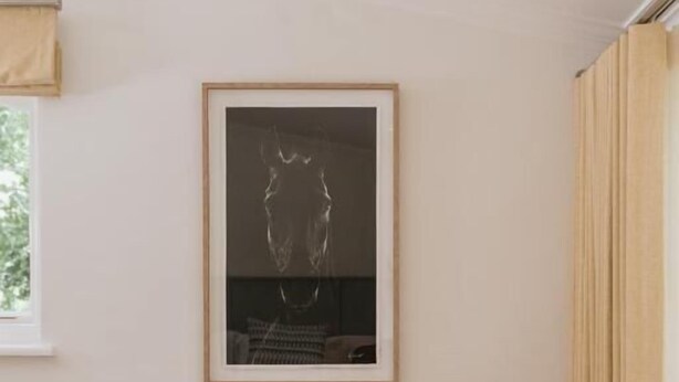 A room with a single brown chair, a small wooden side table, a framed picture on the wall, and a window with curtains. - Klein Champagne Guesthouse and Cottages (Franschhoek)