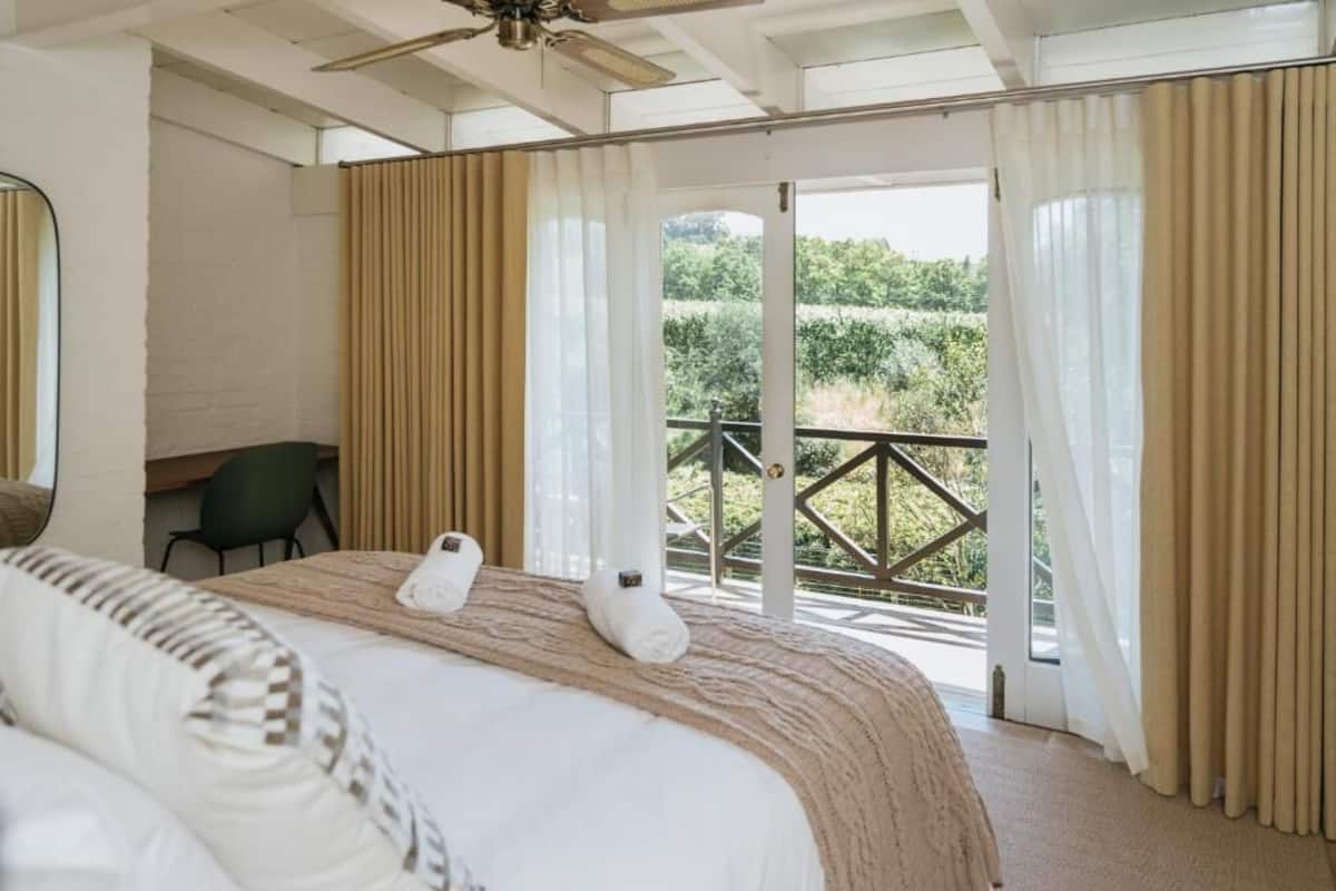 Un dormitorio con cama, una silla y un balcón con cortinas.