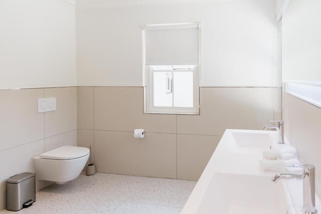 A modern bathroom with a toilet, bidet, sink, and mirror.