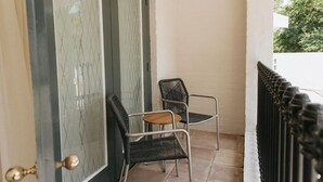 A door with a metal mesh design, two wicker chairs, and a white wall. - Klein Champagne Guesthouse and Cottages (Franschhoek)