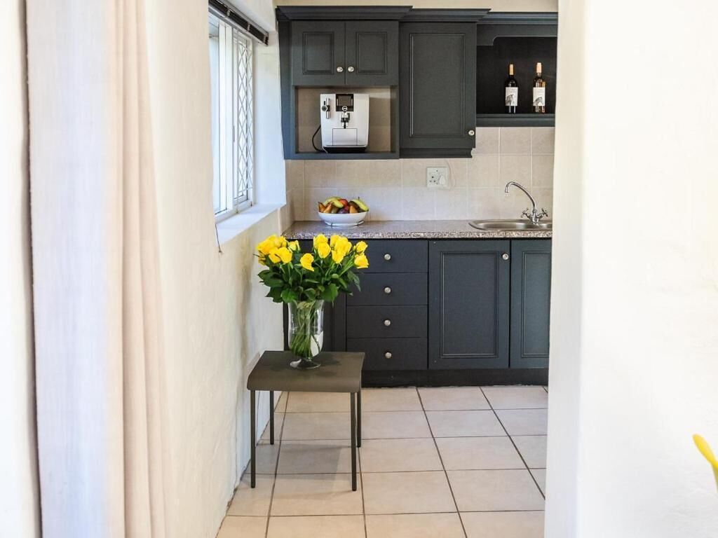 A kitchen with dark cabinets, a countertop, a sink, and a vase with yellow flowers.