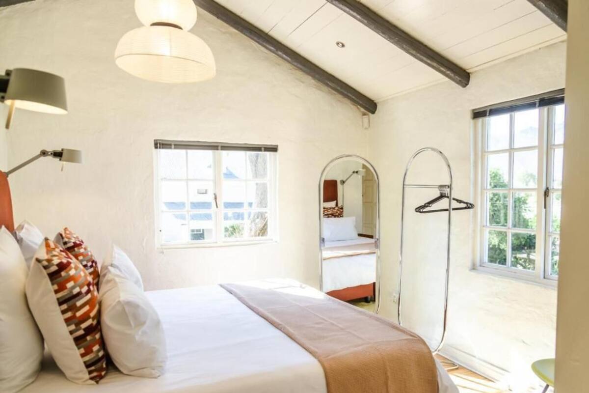 Un dormitorio con cama, lámpara colgante, ventana y espejo.