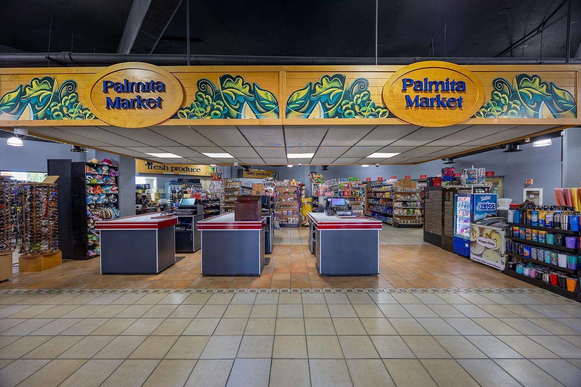 The interior of a market with multiple checkout counters, shelves stocked with various products, and signs indicating sections like 'fresh produce' and 'dairy products'.