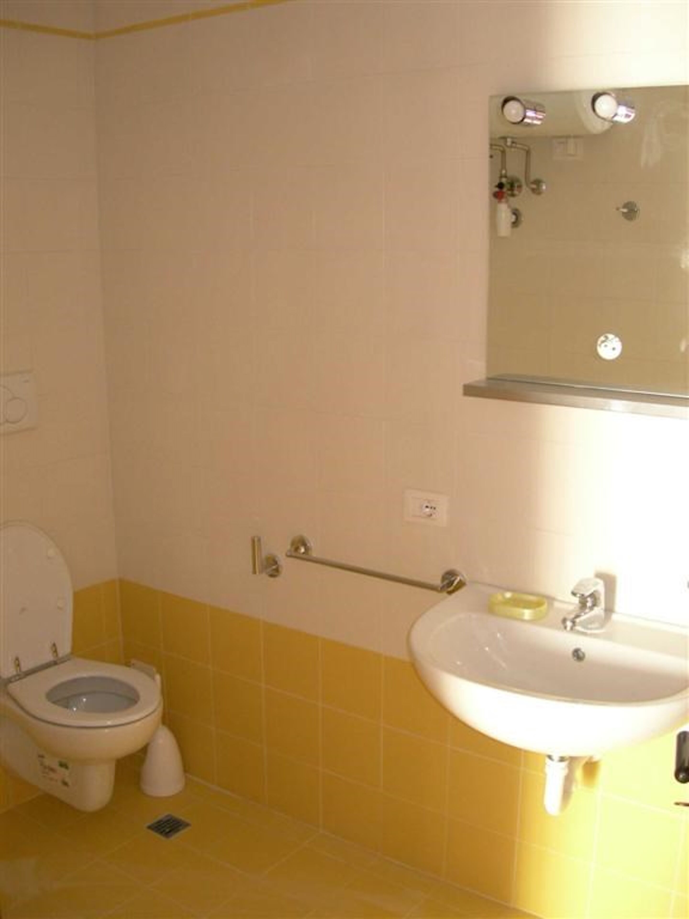 Et badeværelse med toilet, håndvask og spejl.