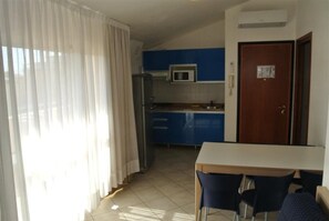 Eine kompakte Küche mit Mikrowelle, Kühlschrank und einem Essbereich mit Tisch und Stühlen.