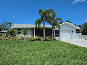 A single-story house with a garage, a covered porch, and a well-maintained lawn. - Canal front, Pool, outdoor kitchen, dock, no bridge, boat landing, Gulf access (Englewood)