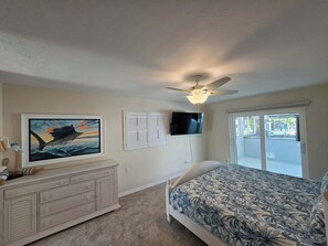 A bedroom with a bed, a dresser, a ceiling fan, a TV, and a window. - Canal front, Pool, outdoor kitchen, dock, no bridge, boat landing, Gulf access (Englewood)