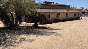 A house with a sandy driveway, a palm tree, and a clear blue sky. - Cancer patients that need peace, quiet, support & proximity to treatment plans. (Cave Creek)