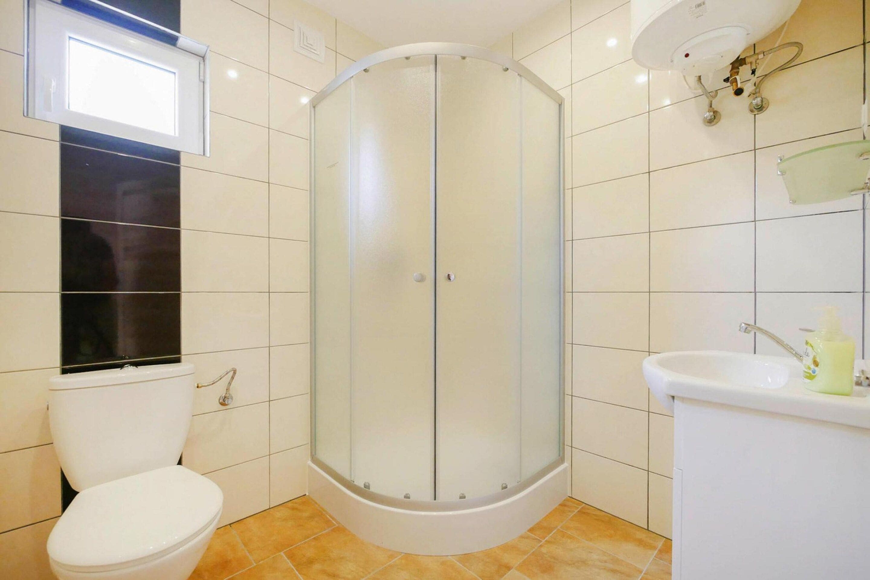 Un baño con ducha de vidrio, inodoro y lavamanos.