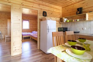 A compact wooden cabin with a kitchenette, a small bed, and a dining area with a table set for two. - Holiday Homes, Attractions for Children (Postomino)