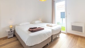 Un dormitorio con cama, mesita de noche, lámpara y vistas al exterior.