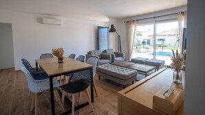 Una sala moderna con una mesa de comedor, sofás y un ventanal grande.