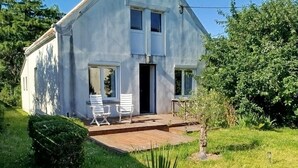 Ein zweigeschossiges Haus mit Veranda, kleinem Garten und Rasen.