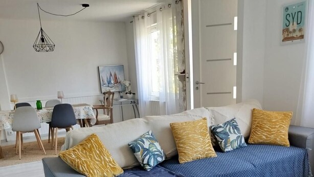 Ein modernes Wohnzimmer mit einer Couch, einem Esstisch und einem Bild an der Wand.