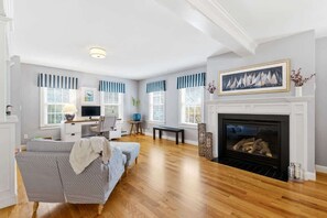 A living room with a fireplace, a sofa, a desk, and a television.