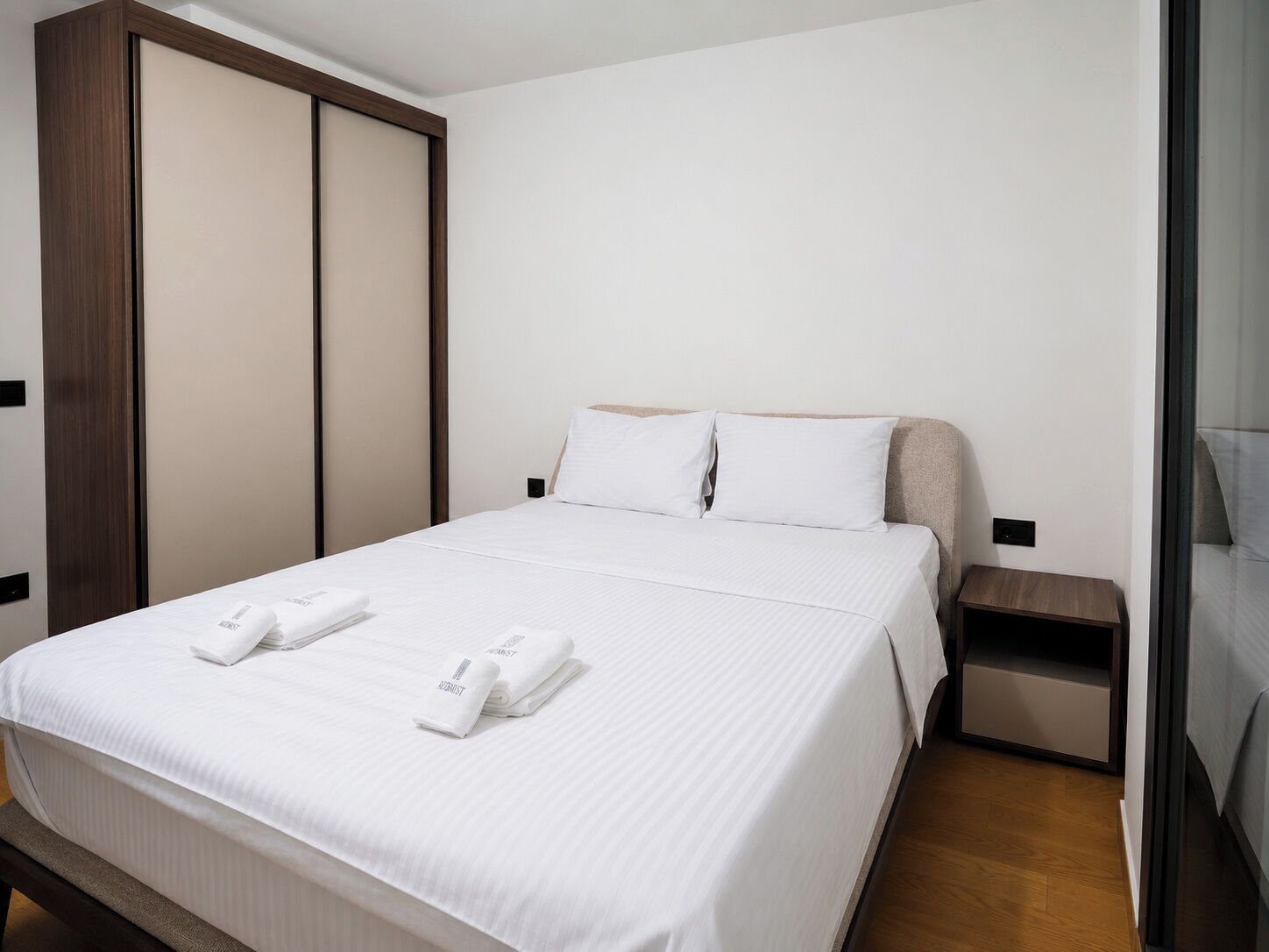 A hotel room with a bed, a nightstand, a wardrobe, and a glass door.
