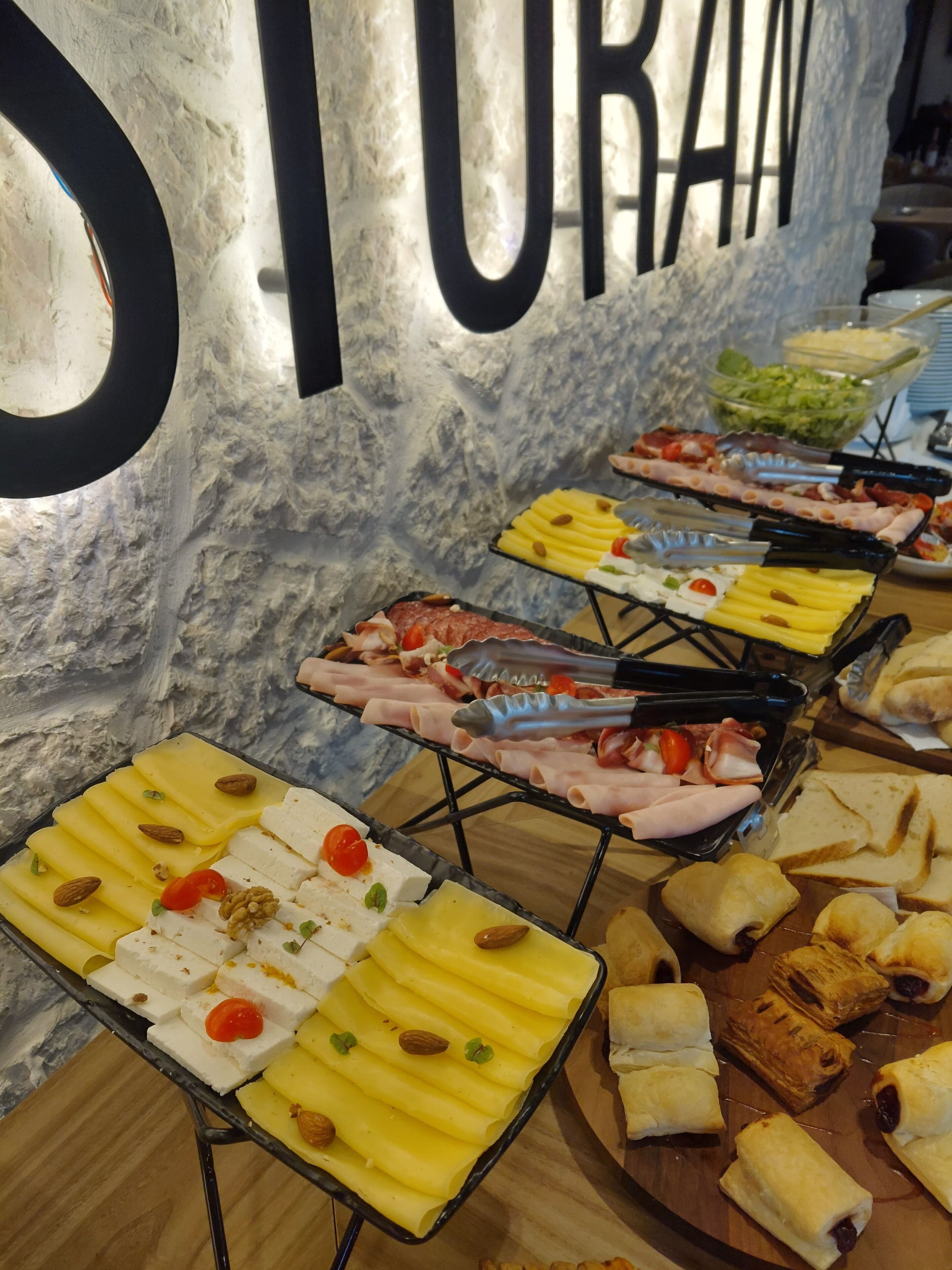 Een buffet met verschillende soorten eten, waaronder kaas, vleeswaren en gebak, gepresenteerd op schalen.