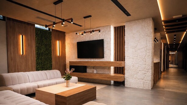 Una sala de estar moderna con un sofá, una mesa de centro y un televisor montado en una pared con textura.