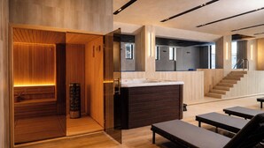 Un interior moderno con sauna, banca de madera, separador de vidrio y una escalera.