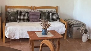 Ein Wohnzimmer mit einer Couch, einem Couchtisch mit einer Vase, einem Holzstuhl und einem Fliesenboden.