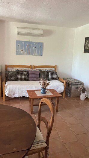 Ein Wohnzimmer mit einer Couch, einem Couchtisch mit einer Vase, einem Holzstuhl und einem Fliesenboden.