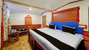 Een slaapkamer met een bed, een houten bankje, een tafel met dienblad en een raam met gordijnen.
