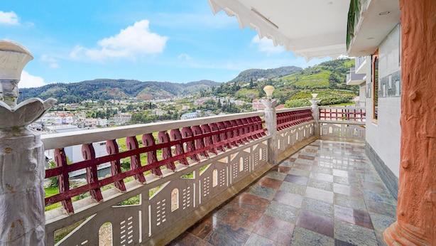 Een balkon met uitzicht op een heuvelachtig landschap en een verafgelegen stad.