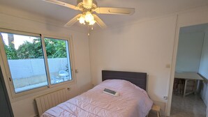 Un dormitorio con cama, ventilador de techo, ventana y vistas al exterior.