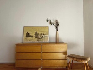 A wooden dresser with drawers, a framed picture on top, and a vase with dried flowers. - Beautiful apartment directly at the Kurwald (Bad Lippspringe)