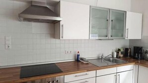 Eine Küche mit weißen Schränken, einer Edelstahl-Dunstabzugshaube, einer doppelten Spüle und einer Holzarbeitsplatte.