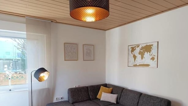 Ein modernes Wohnzimmer mit einem Ecksofa, einer Stehlampe und einer Weltkarte an der Wand.