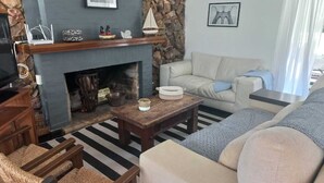 A living room with a fireplace, a sofa, a coffee table, and a stone wall. - Tile villa in residential neighborhood, 3 minutes from the beach. (Punta del Este)