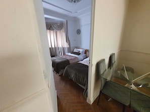 Ein Schlafzimmer mit zwei Betten, einer Wanduhr und einem Fenster mit Vorhängen.